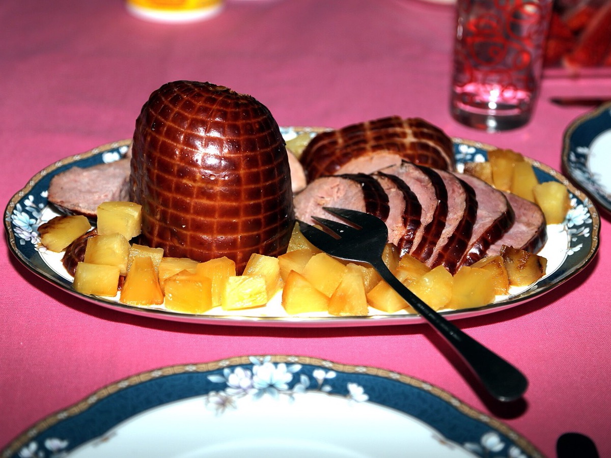A whole smoked ham, partly sliced, on a platter